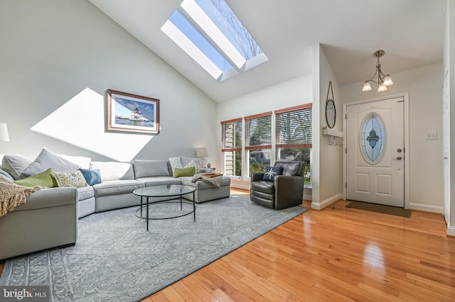 living area featuring a skylight, high vaulted ceiling, wood-type flooring, and a notable chandelier