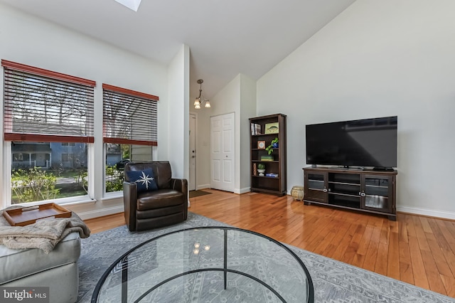 living area with wood finished floors, high vaulted ceiling, and baseboards