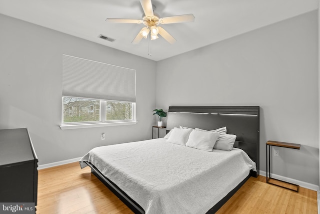 bedroom featuring baseboards, wood finished floors, visible vents, and a ceiling fan