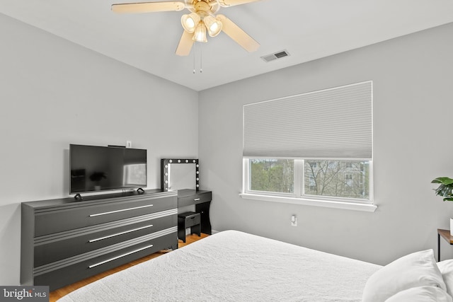 bedroom with a ceiling fan, wood finished floors, and visible vents