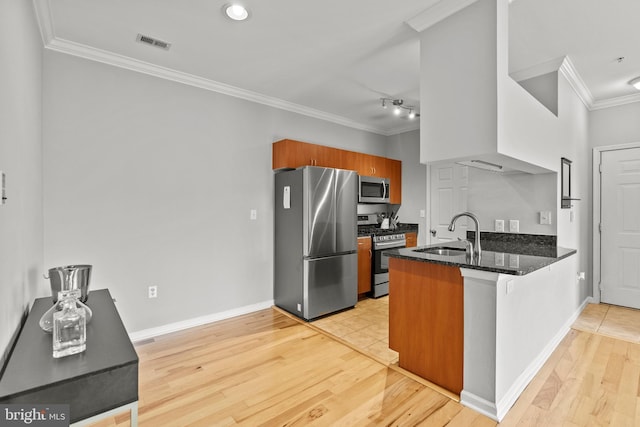 kitchen with a sink, stainless steel appliances, a peninsula, ornamental molding, and visible vents