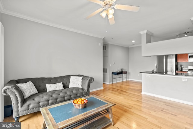 living area with a ceiling fan, crown molding, light wood-style floors, baseboards, and recessed lighting