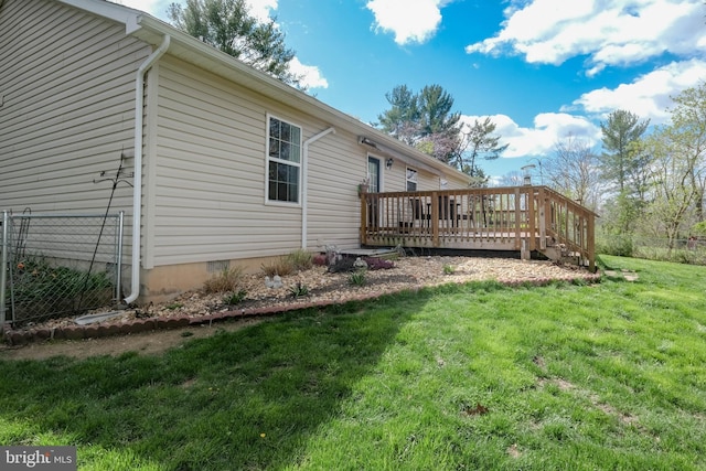 rear view of property featuring a wooden deck, a lawn, and fence