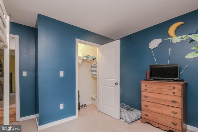 bedroom with a closet, a spacious closet, carpet flooring, and baseboards