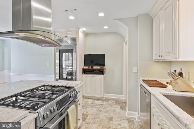 kitchen with stone tile flooring, island exhaust hood, light stone countertops, and appliances with stainless steel finishes