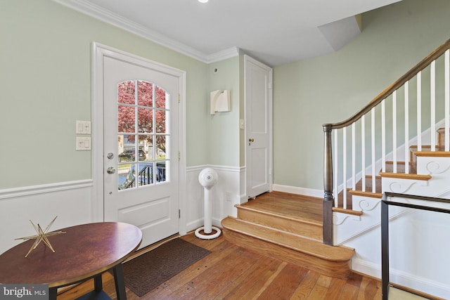 entryway with wood-type flooring, crown molding, and stairs