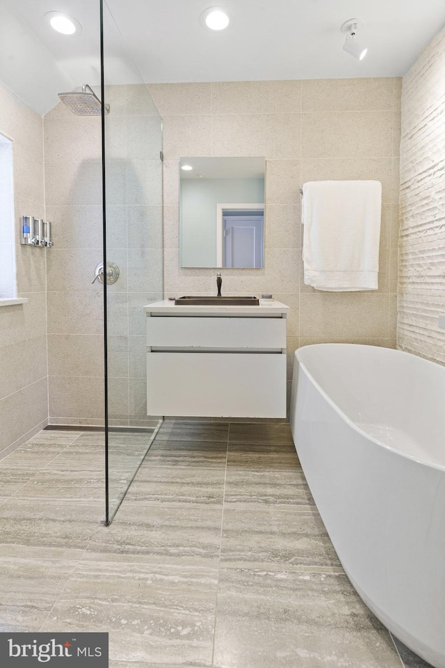 full bath featuring a freestanding bath, vanity, a walk in shower, and recessed lighting
