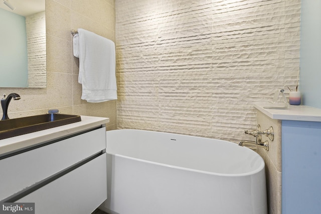 bathroom featuring tile walls, a freestanding tub, and vanity