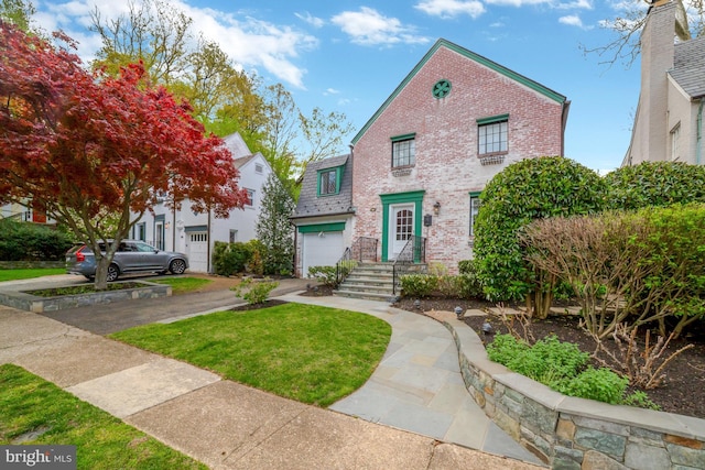 view of front of house with an attached garage, driveway, a front lawn, and brick siding