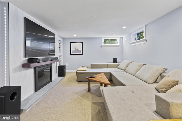 living area featuring light carpet, a glass covered fireplace, and recessed lighting