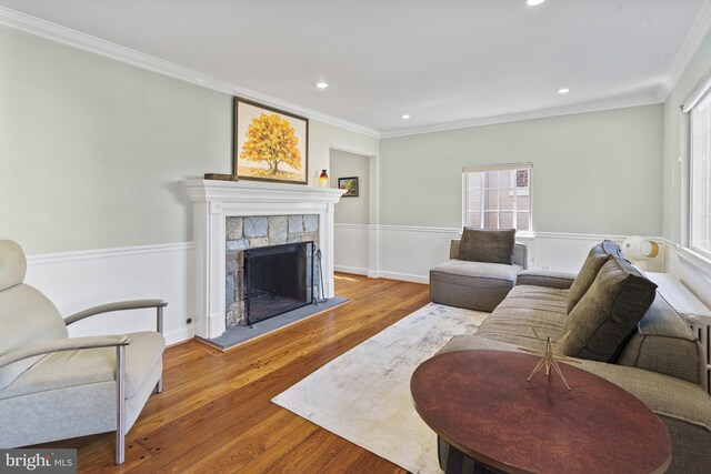 living area featuring recessed lighting, wood finished floors, a fireplace with raised hearth, and ornamental molding