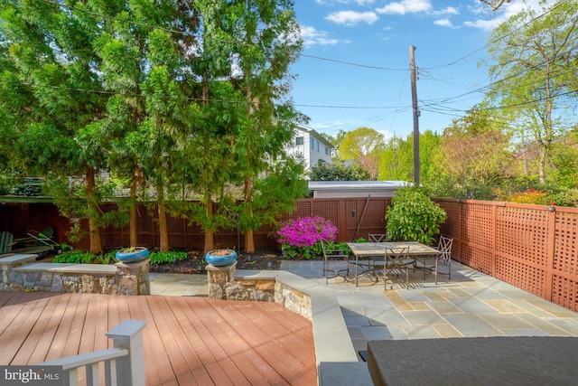 view of patio / terrace featuring a wooden deck, a fenced backyard, and outdoor dining area