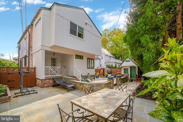 rear view of house with fence, outdoor dining space, a shed, a patio area, and an outbuilding