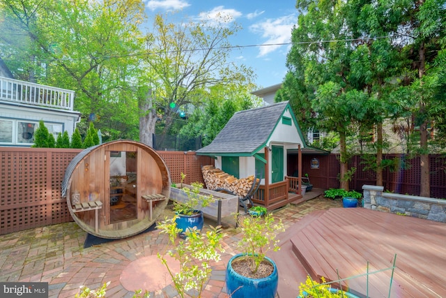 view of patio / terrace with a wooden deck, a fenced backyard, and an outbuilding