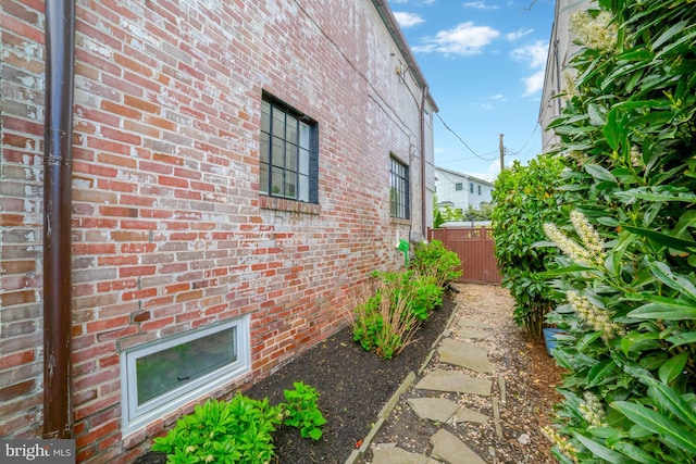 view of property exterior with brick siding and fence