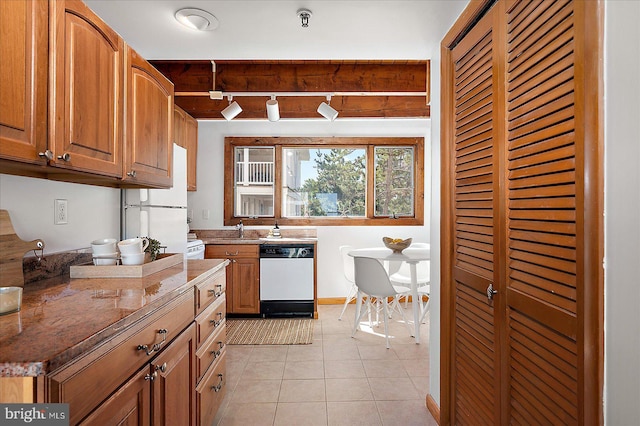 kitchen featuring track lighting, white appliances, light tile patterned floors, light stone countertops, and a sink