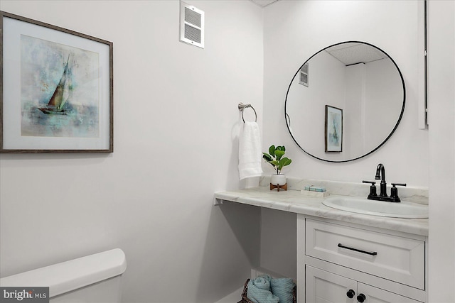 bathroom featuring visible vents, toilet, and vanity