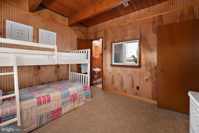 bedroom featuring ensuite bath, beamed ceiling, carpet, and wood walls