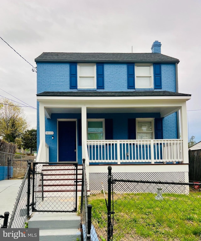 american foursquare style home featuring covered porch, a gate, brick siding, and a chimney
