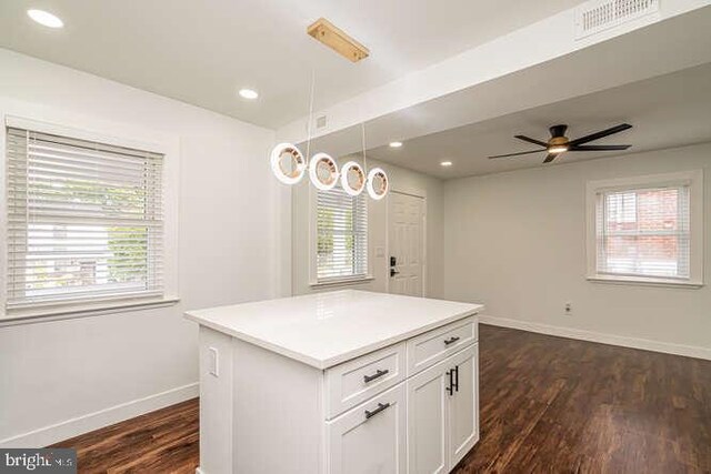kitchen with baseboards, dark wood-style floors, white cabinetry, ceiling fan, and a kitchen island