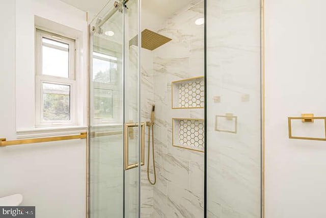 bathroom featuring a marble finish shower and toilet