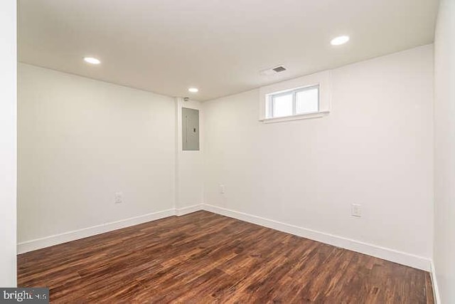 below grade area featuring dark wood-style floors, baseboards, recessed lighting, and electric panel