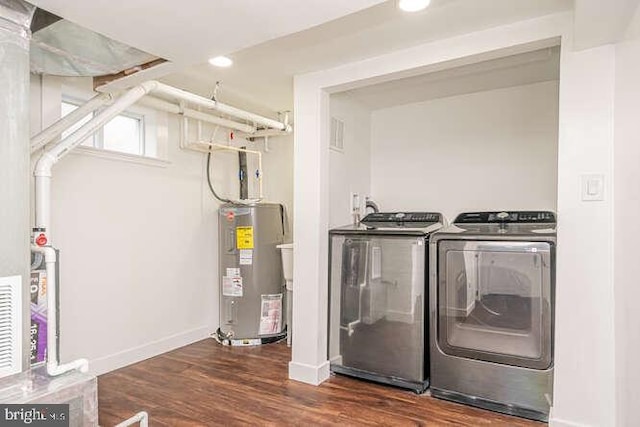 washroom featuring washing machine and dryer, water heater, wood finished floors, baseboards, and recessed lighting