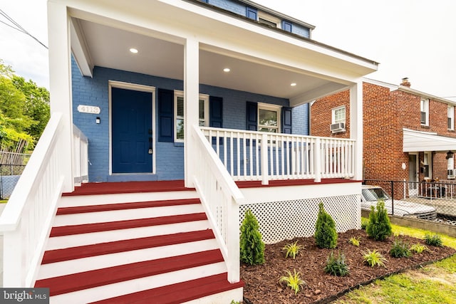 doorway to property with brick siding, a porch, and cooling unit