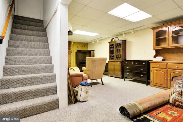 interior space featuring a paneled ceiling, rail lighting, stairway, and carpet