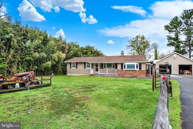 ranch-style house with a front yard, an outbuilding, a chimney, covered porch, and brick siding