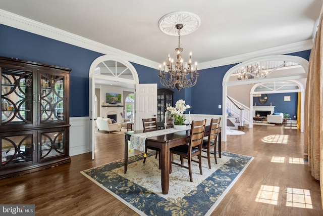 6601 Rutledge Dr, Fairfax Station, VA 22039 - dining space featuring arched walkways, wainscoting, a chandelier, ornamental molding, and stairs