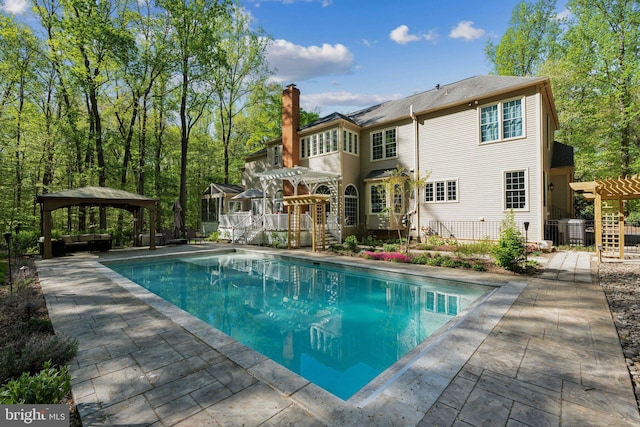 6601 Rutledge Dr, Fairfax Station, VA 22039 - back of property with a pergola, a patio, an outdoor pool, a chimney, and a gazebo