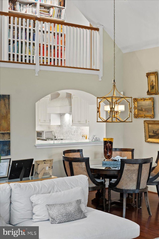 dining space with high vaulted ceiling, an inviting chandelier, and wood finished floors