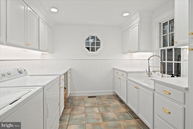 laundry room with visible vents, a wainscoted wall, a sink, washer and dryer, and cabinet space