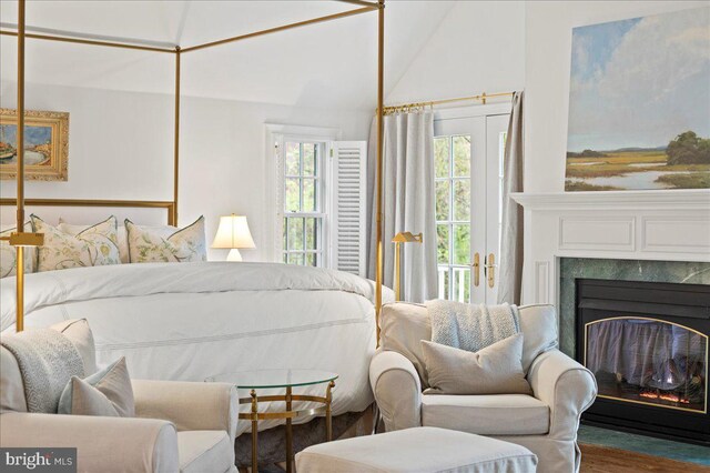 bedroom with a fireplace with flush hearth, wood finished floors, and lofted ceiling