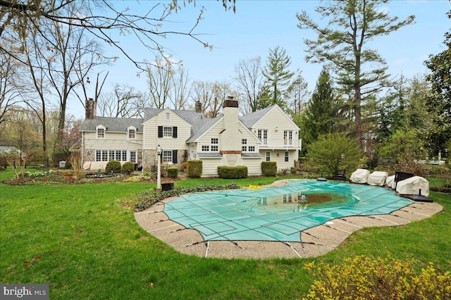 view of swimming pool featuring a covered pool, a patio area, and a lawn