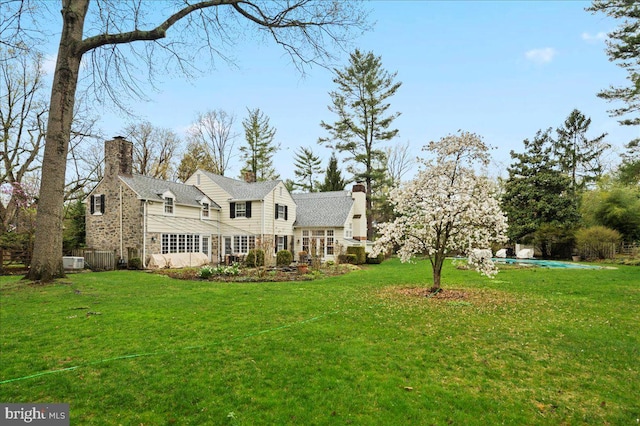 exterior space featuring a front yard, stone siding, and a chimney