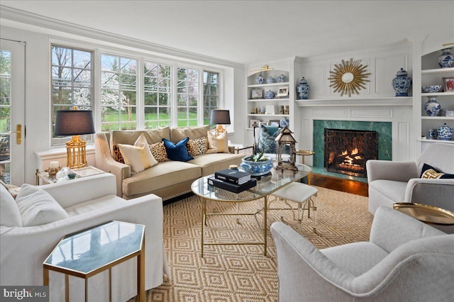 living area with ornamental molding, built in shelves, wood finished floors, and a premium fireplace