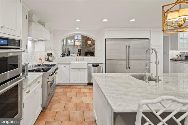 kitchen with high end appliances, decorative backsplash, a sink, and white cabinetry