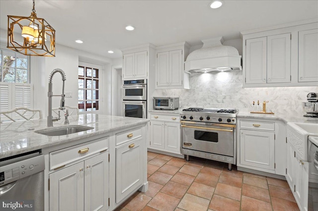 kitchen featuring tasteful backsplash, white cabinets, a sink, appliances with stainless steel finishes, and premium range hood