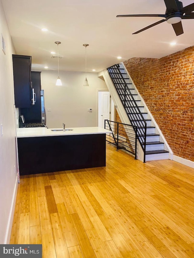unfurnished living room featuring light wood-style floors, baseboards, ceiling fan, and a sink