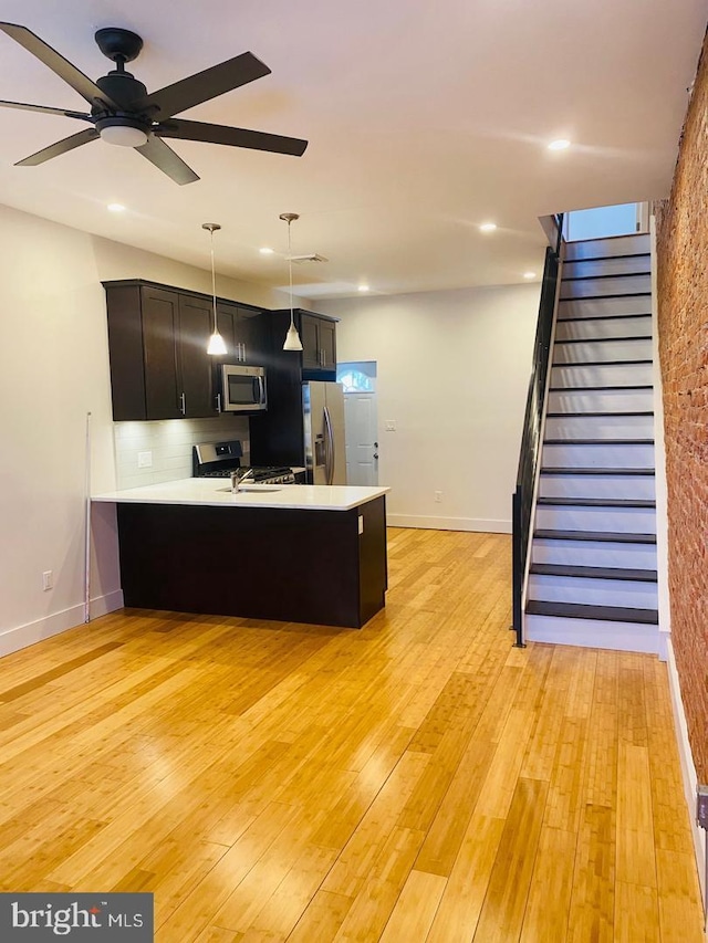kitchen with a peninsula, light countertops, light wood-type flooring, and appliances with stainless steel finishes