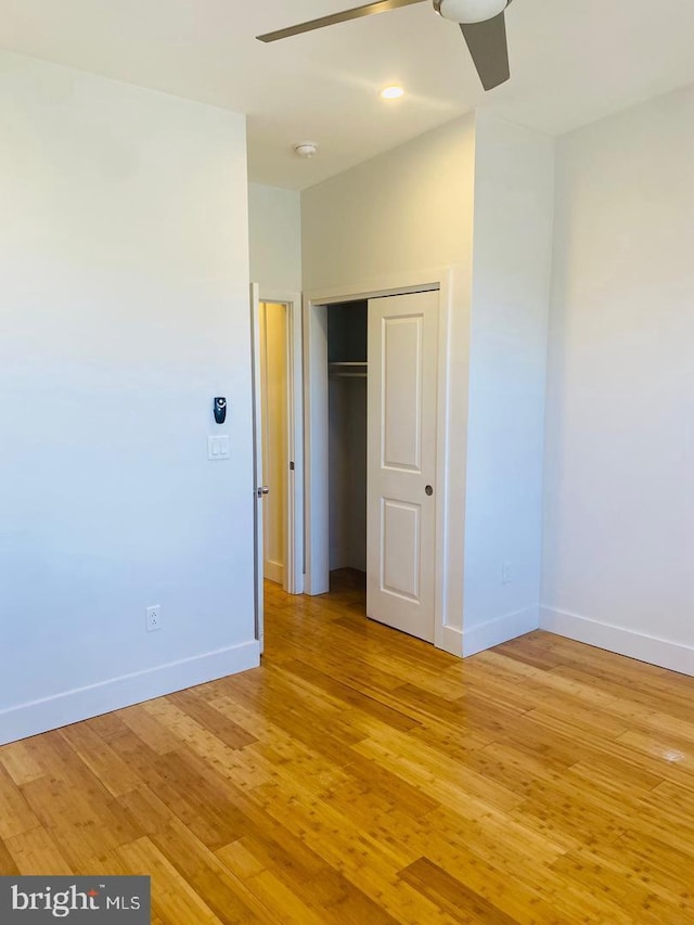 unfurnished bedroom featuring light wood-type flooring, ceiling fan, baseboards, and a closet