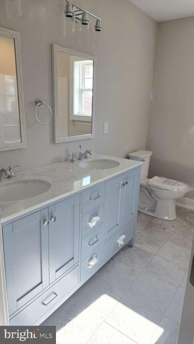 full bathroom featuring double vanity, marble finish floor, a sink, and toilet