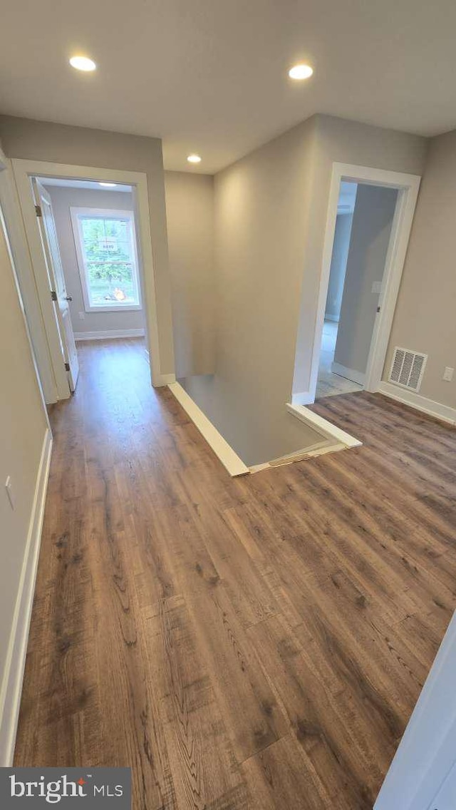 corridor featuring visible vents, baseboards, recessed lighting, and wood finished floors