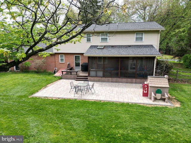 rear view of property featuring fence, roof with shingles, a sunroom, a patio area, and a lawn