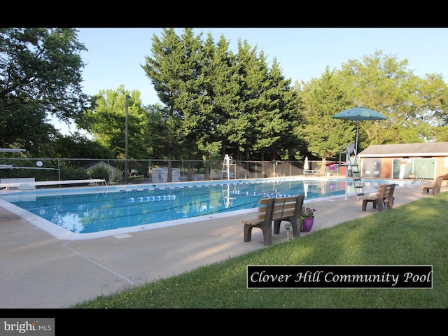 community pool with a lawn, a patio area, and fence