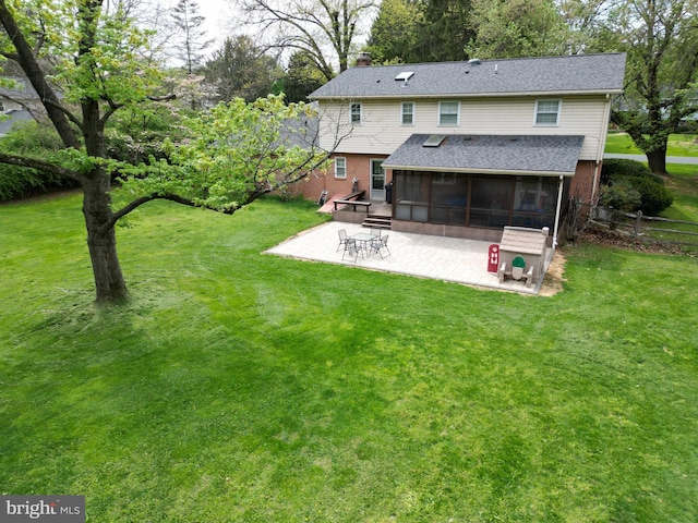 back of house featuring a patio, a chimney, a sunroom, brick siding, and a lawn