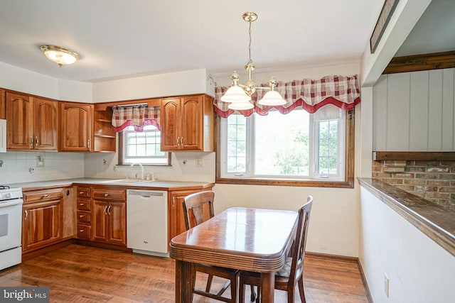 kitchen with a chandelier, white appliances, brown cabinetry, and a sink