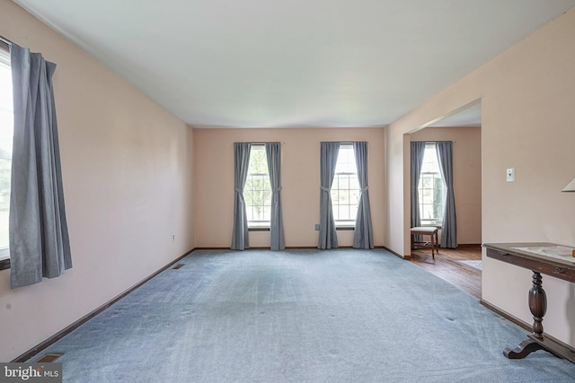 unfurnished living room featuring baseboards, a healthy amount of sunlight, and carpet flooring